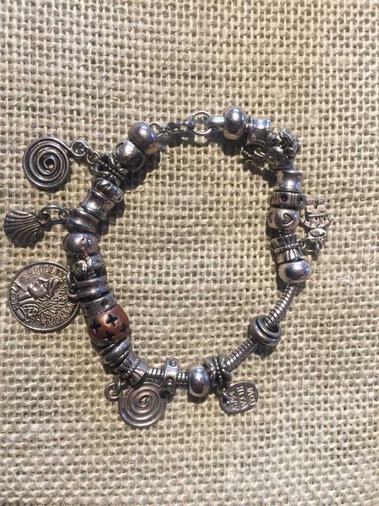 Bracelet 428, a silver-tone charm bracelet with spiral, shell and coin charms